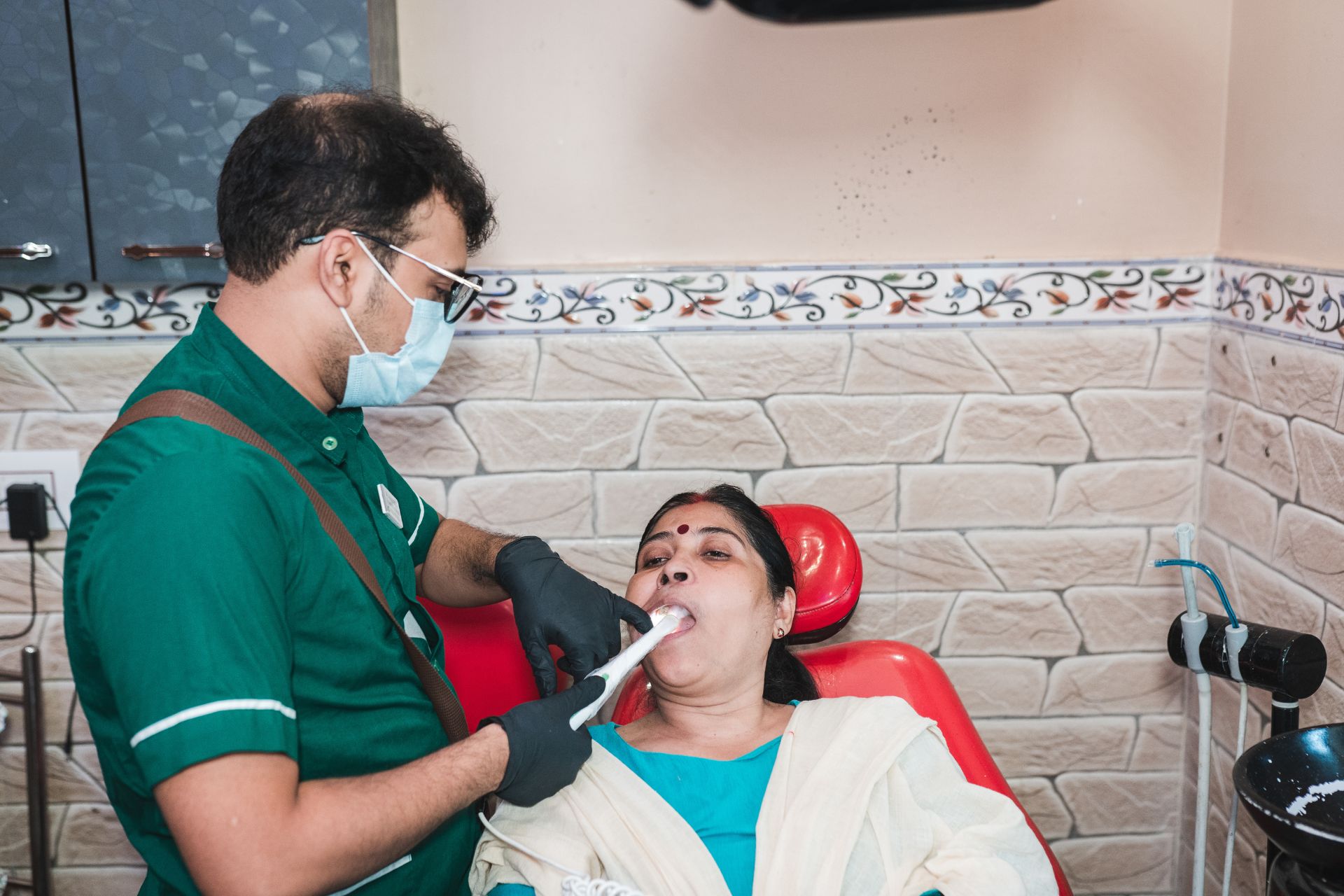 Dentist using intraoral scanner to capture digital impression of woman’s teeth during dental checkup.