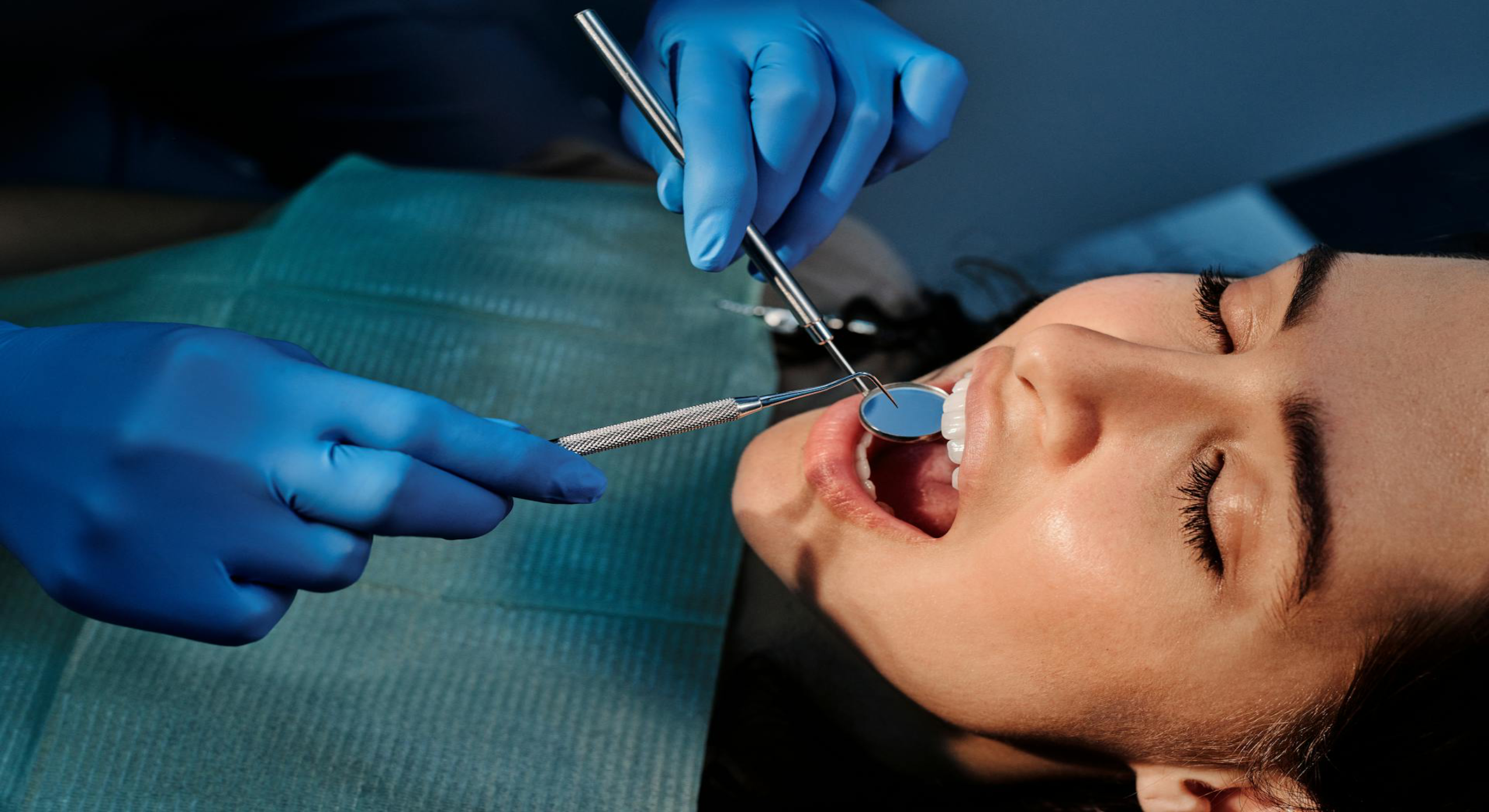 Dentist examining a patient’s teeth using a dental mirror and probe during an oral check-up.