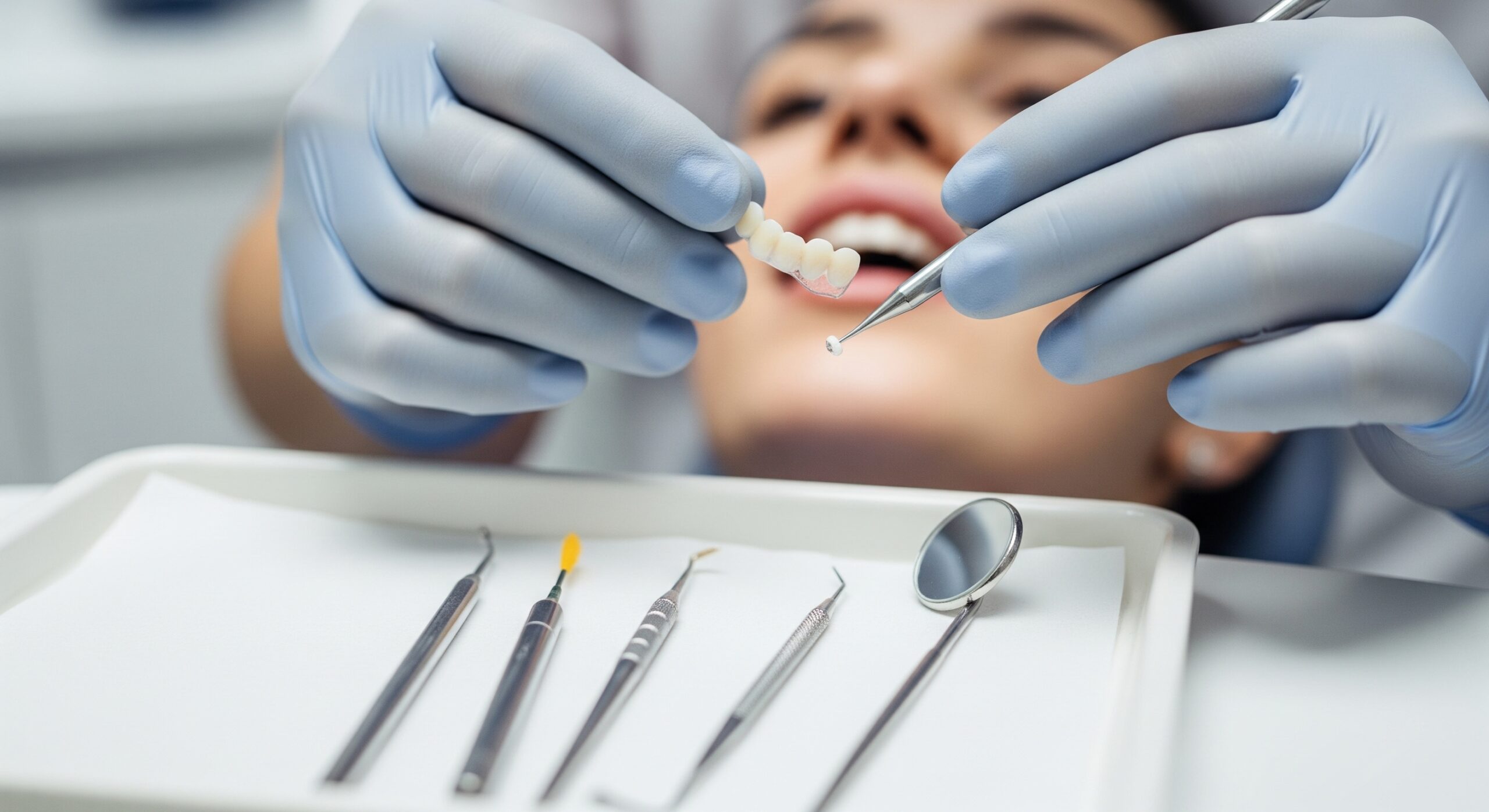 Dentist preparing a dental bridge and bonding material while the patient waits during a restorative procedure.